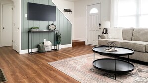 Una sala de estar moderna con una escalera, un televisor de pantalla plana, un sofá y una mesa de centro.