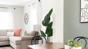 Una sala de estar moderna con una mesa de comedor de madera, un sofá y una planta grande.