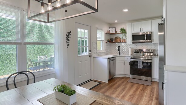 Una cocina moderna con armarios blancos, electrodomésticos de acero inoxidable y piso de madera.
