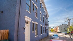 Un immeuble de deux étages avec une façade bleue, une échelle de secours et une porte d’entrée bien visible.