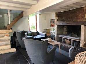 Una sala de estar con sofá, sillas, una mesa, chimenea y escalera.