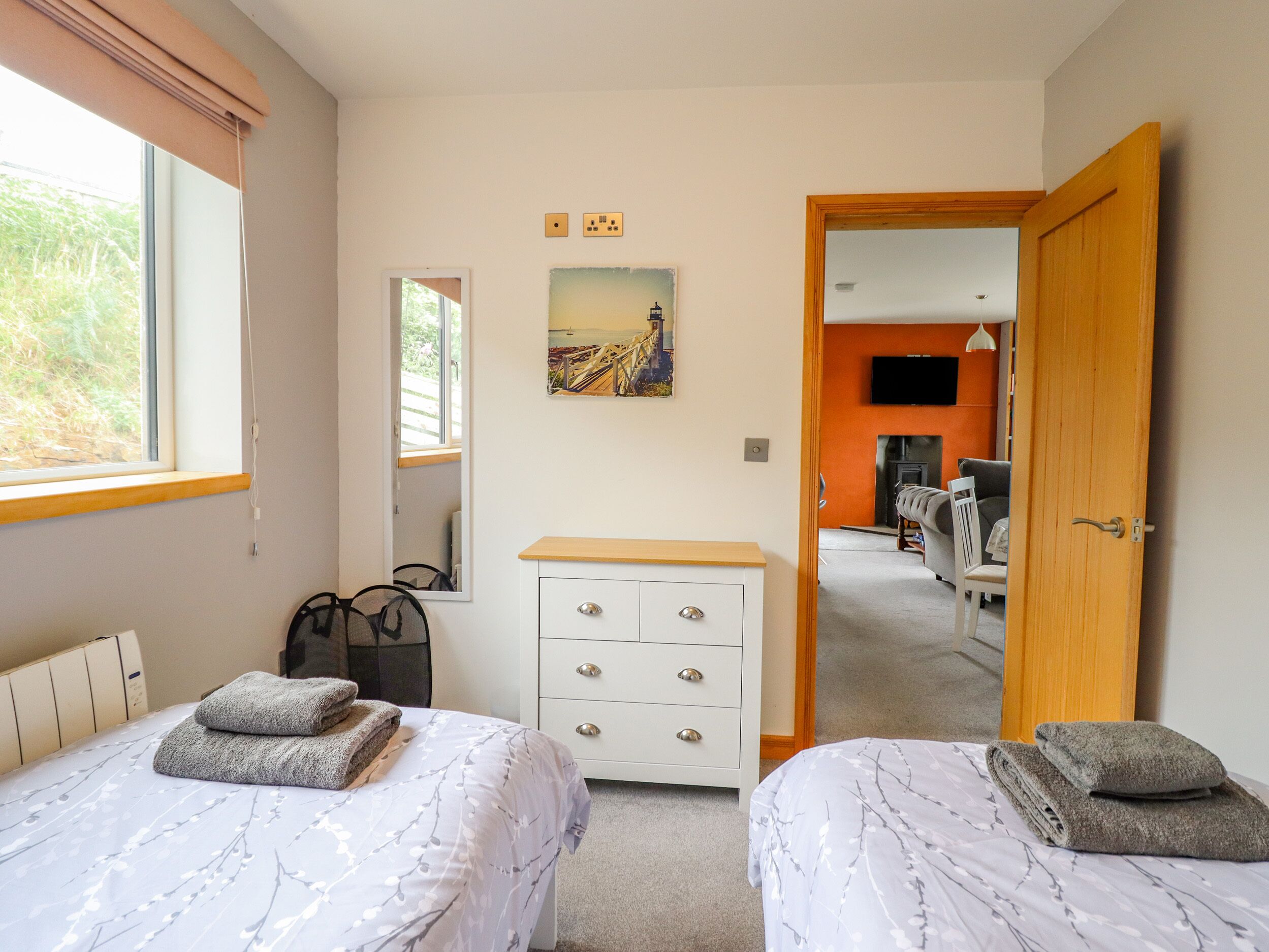 Quarto com duas camas, cômoda, espelho e um quadro.
