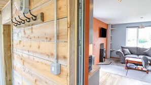 Un salon moderne avec un mur en bois, une cheminée, un canapé gris et un téléviseur fixé au mur.