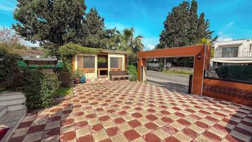 A courtyard with a patterned tile floor, a wooden bench, and a small covered seating area.