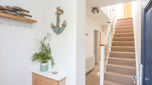 A hallway with a staircase, a potted plant, and decorative wall art.