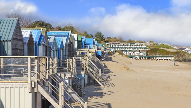 A row of beach huts with wooden staircases leading to the beach.