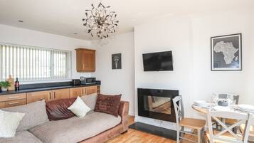 Una sala de estar moderna con sofá, chimenea, zona de cocina y mesa de comedor.