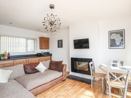 Una sala de estar moderna con sofá, chimenea, zona de cocina y mesa de comedor.
