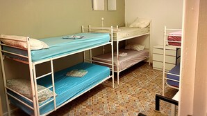 A dormitory room with bunk beds, a small desk, and a patterned floor. - Cathedral Malaga Hostal - Hostel (Málaga)