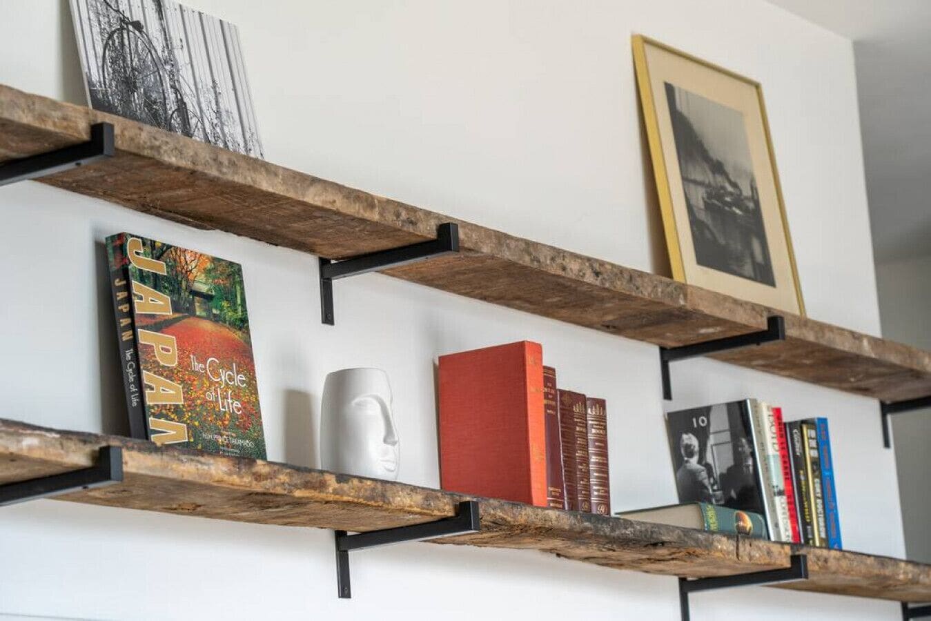 A bookshelf with books and a framed picture on a wall.