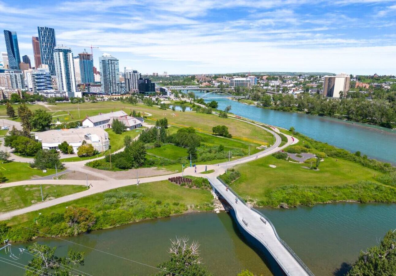A river with a bridge, a city skyline, and a park with pathways.