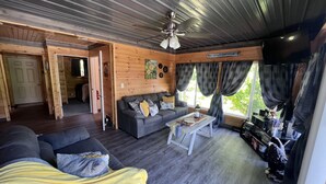Interior acogedor de una cabaña con sofá, una mesa de centro y un ventilador de techo.