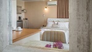 Una habitación de hotel con cama, mesita de noche y una pequeña zona de kitchenette.