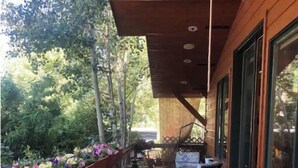 A wooden deck with a table and chairs, surrounded by potted plants and a metal fence. - Feel like a Local in Aspen (Aspen)