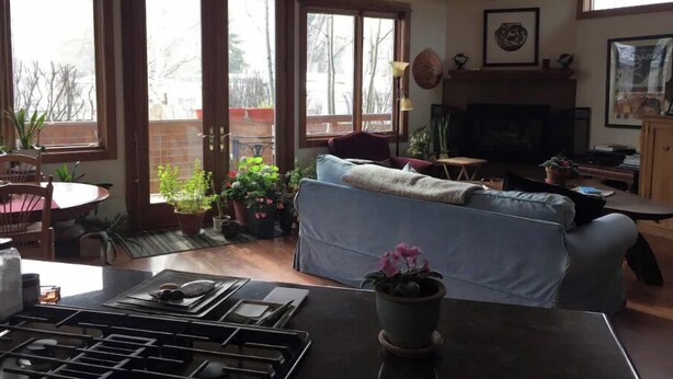 A cozy living room with a sofa, a dining table with chairs, a fireplace, and large windows offering a view of the outdoors. - Feel like a Local in Aspen (Aspen)
