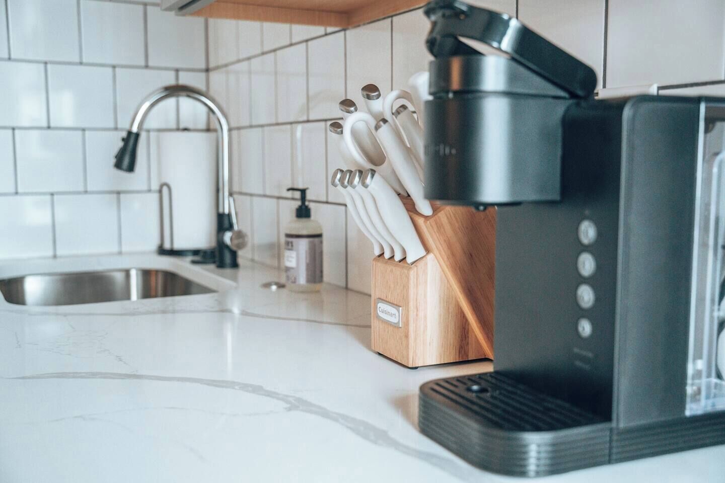 A kitchen with a coffee maker, a knife block, and a faucet.
