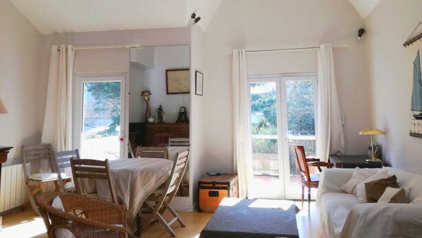 Ein geräumiges Wohnzimmer mit Essbereich, großen Fenstern und Blick auf Grünflächen.