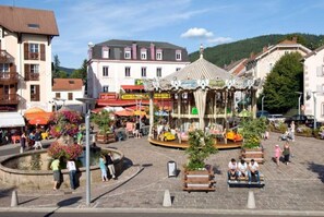 A public square with a carousel, benches, and a fountain.
