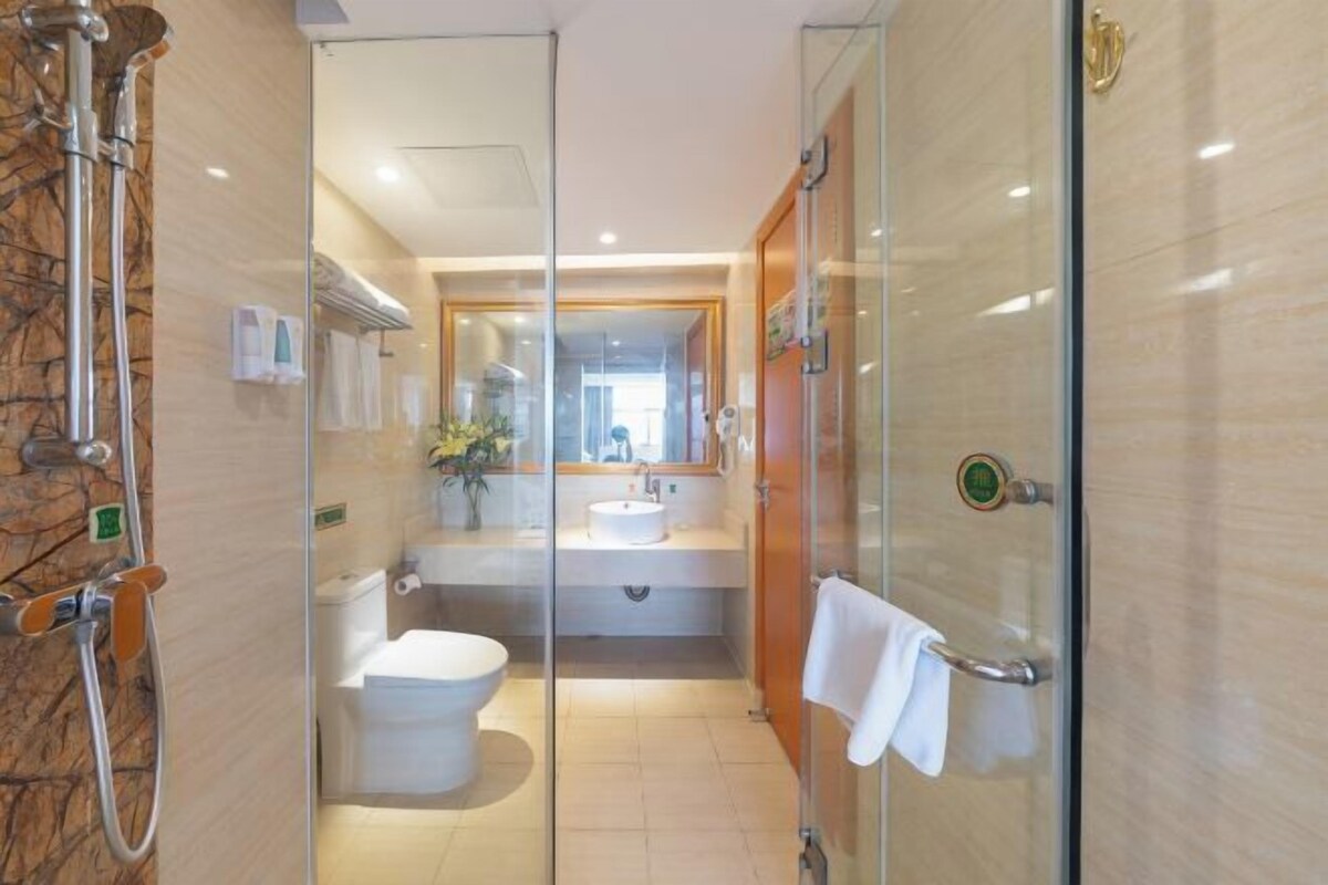 A modern bathroom with a glass shower enclosure, a toilet, and a sink.