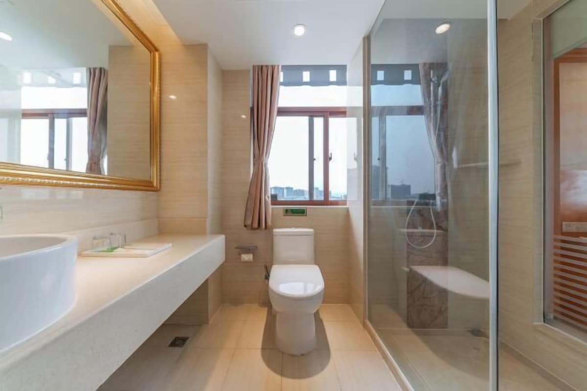 A modern bathroom with a large mirror, a toilet, and a shower area.