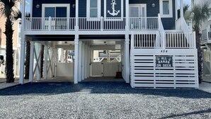 A multi-story building with a dark facade, white railings, and a prominent anchor symbol. - Beach House w/beautiful ocean views.  Private heated pool. Elevator. Sleeps 10. (Ocean Isle Beach)