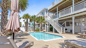 A pool area with lounge chairs, a wooden deck, and a staircase leading to an upper level. - Beach House w/beautiful ocean views.  Private heated pool. Elevator. Sleeps 10. (Ocean Isle Beach)