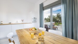Una cocina moderna con una mesa de comedor de madera, un tazón de fruta y dos vasos de jugo de naranja.