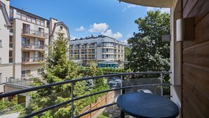 Un balcone con tavolo e sedie, vista su una zona residenziale con diversi edifici e cielo sereno.