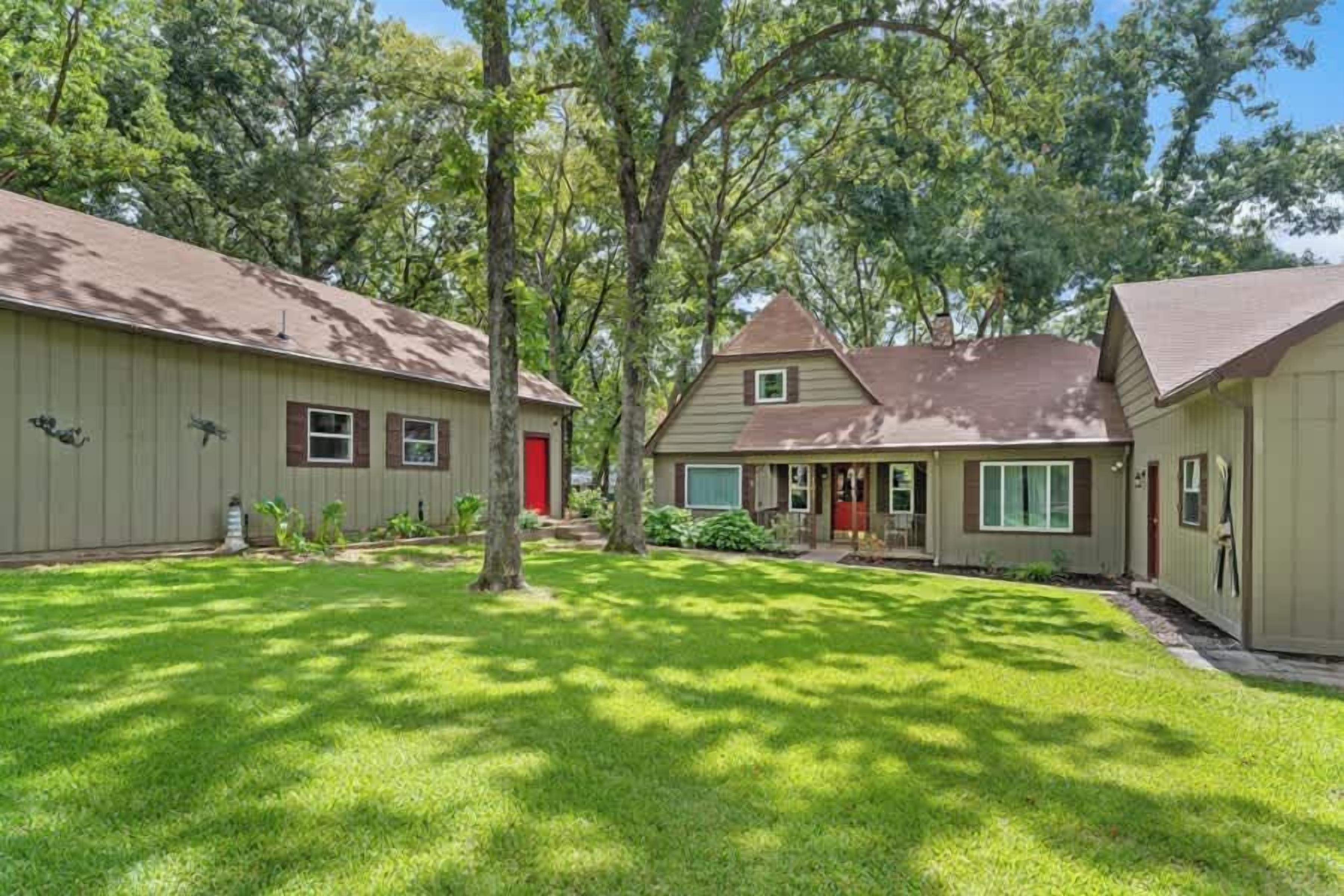 A residential property with a well-maintained lawn, a house with a brown roof, and a red door.