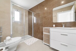 Features a sleek vanity, glass-enclosed shower, and toilet with a convenient towel.