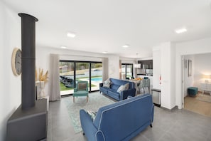 A modern living room with a sofa, a coffee table, and a fireplace. There is a dining area with a table and chairs.