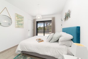 Une chambre à coucher comprenant un lit, une table de chevet, un luminaire suspendu et une fenêtre donnant sur un paysage agréable.