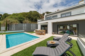 Une maison moderne dotée d’une piscine, de mobilier d’extérieur et d’un espace patio.