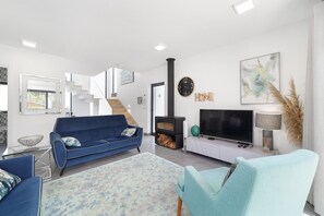 Un salon moderne avec un canapé, un téléviseur, une cheminée et un escalier menant à un autre niveau.
