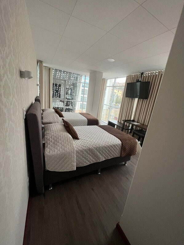 A modern hotel room with a large bed, a flat-screen TV, and a city view. - NOVUM HOTEL (La Paz)