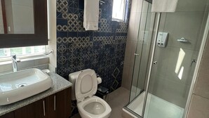 A modern bathroom with a sink, toilet, and shower. - NOVUM HOTEL (La Paz)