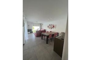 Amplia sala de estar con una mesa de comedor y sillas, un sofá rojo y un televisor.