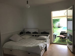 Un dormitorio con cama, mesita de noche y vistas a un área exterior con patio y piscina.