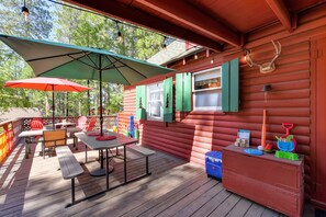 Relax on the deck with a picnic table and benches, surrounded by comfortable seating and a large umbrella for shade.