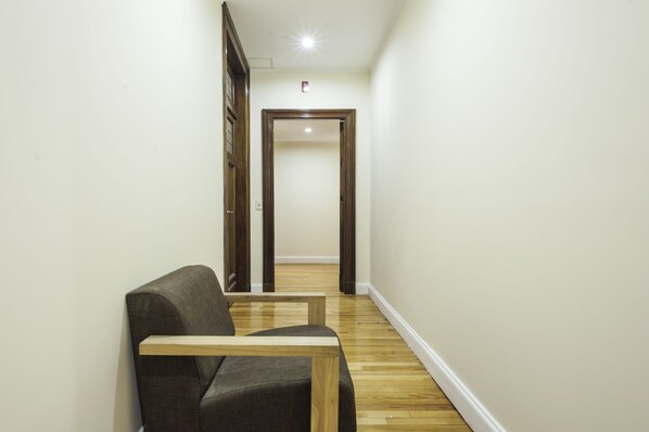 A hallway with a wooden floor, a dark-colored sofa, and a wooden door at the end.