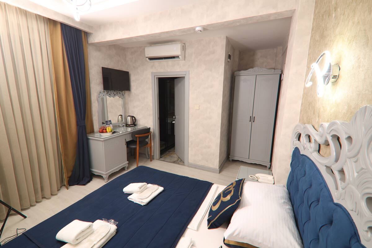 A hotel room with a bed, a desk, a wardrobe, and a bathroom.