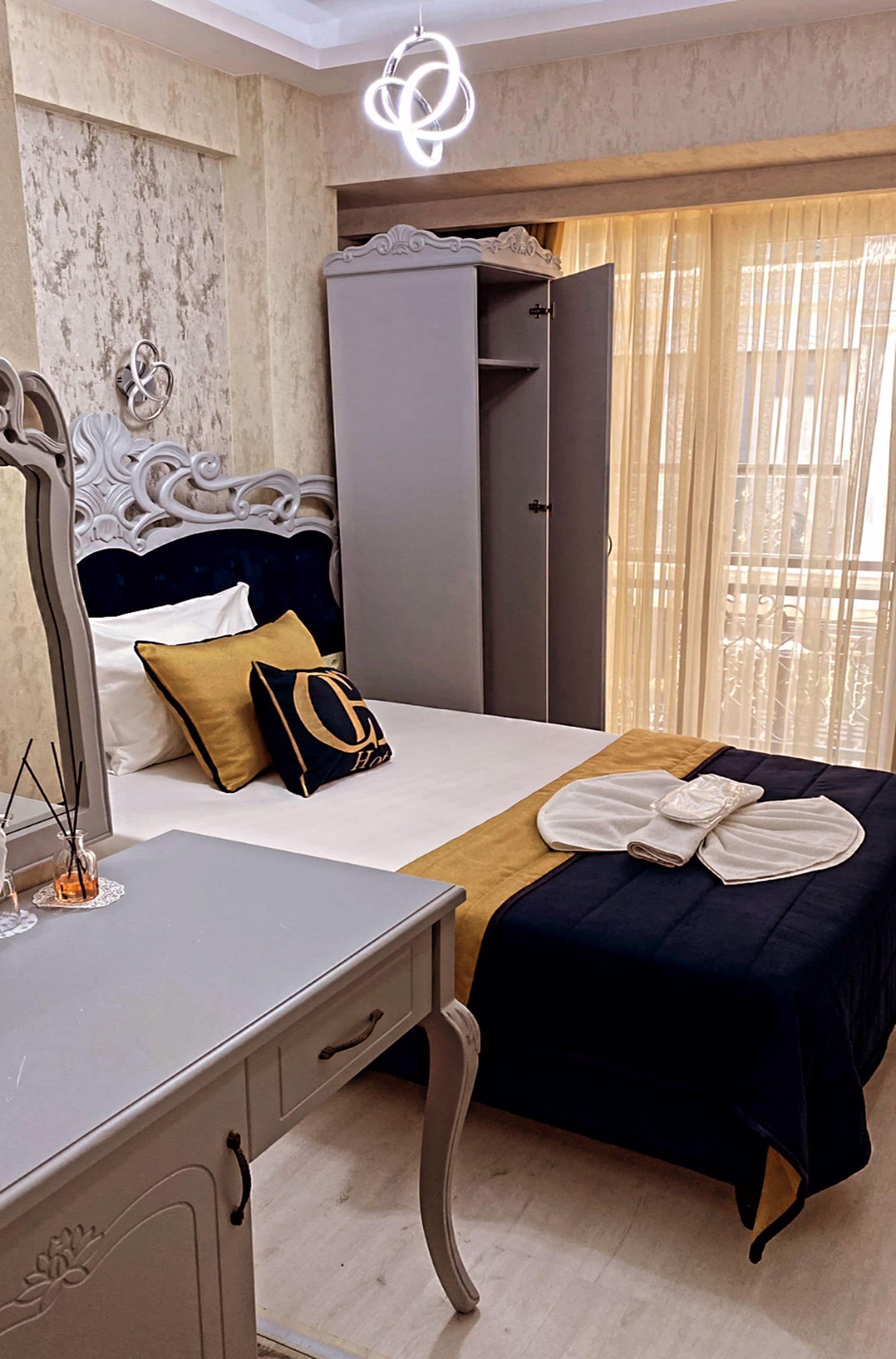 A hotel room with a bed, bedside table, wardrobe, and a large mirror.