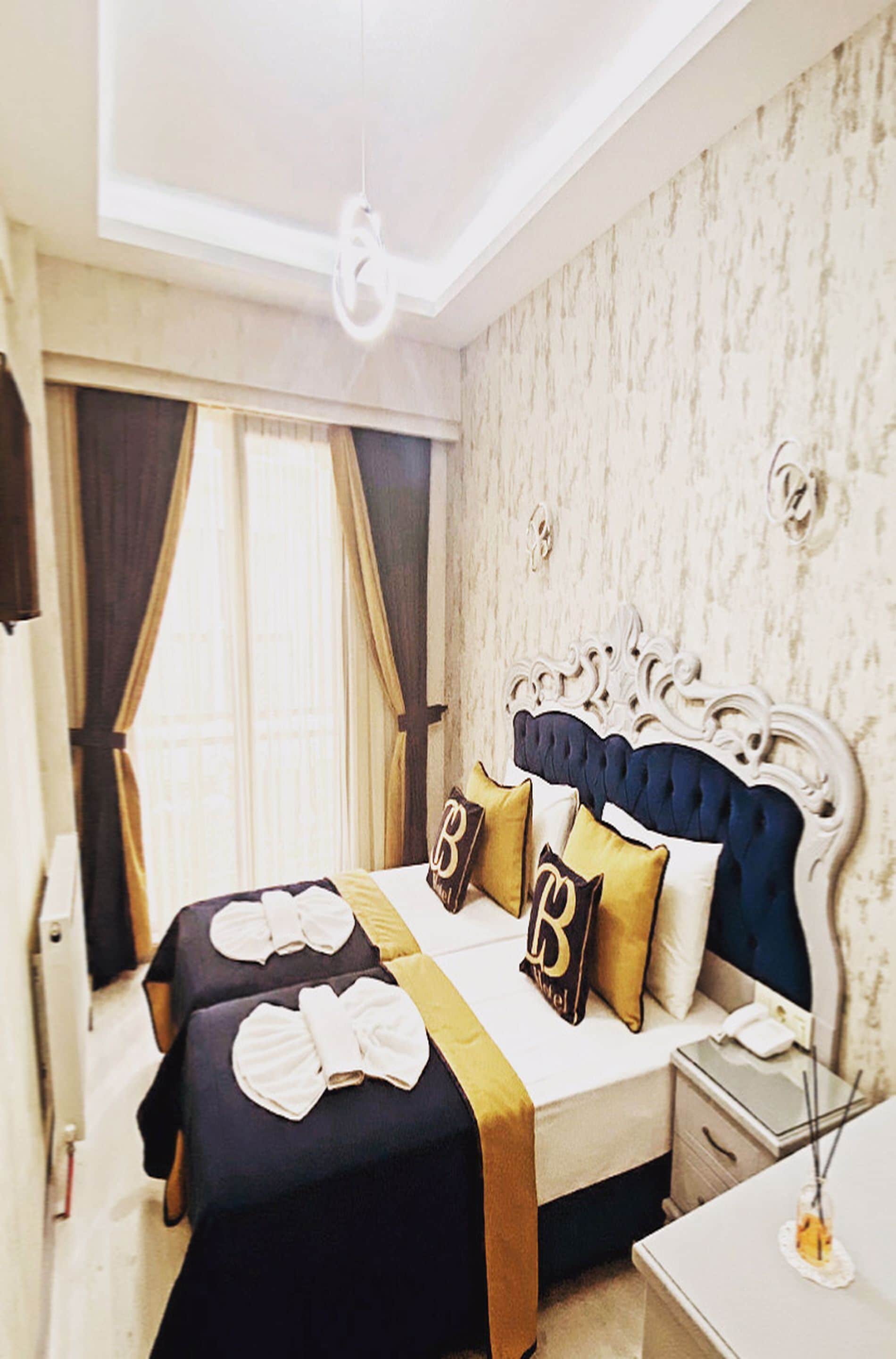 Une chambre d’hôtel avec un grand lit, une table de chevet, une commode et une fenêtre avec des rideaux.