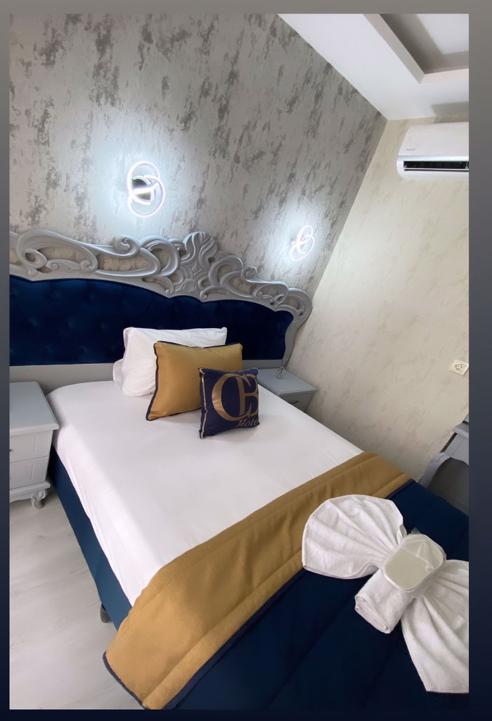 Un dormitorio con cama, mesitas de noche, un cabecero decorativo y un equipo de aire acondicionado.