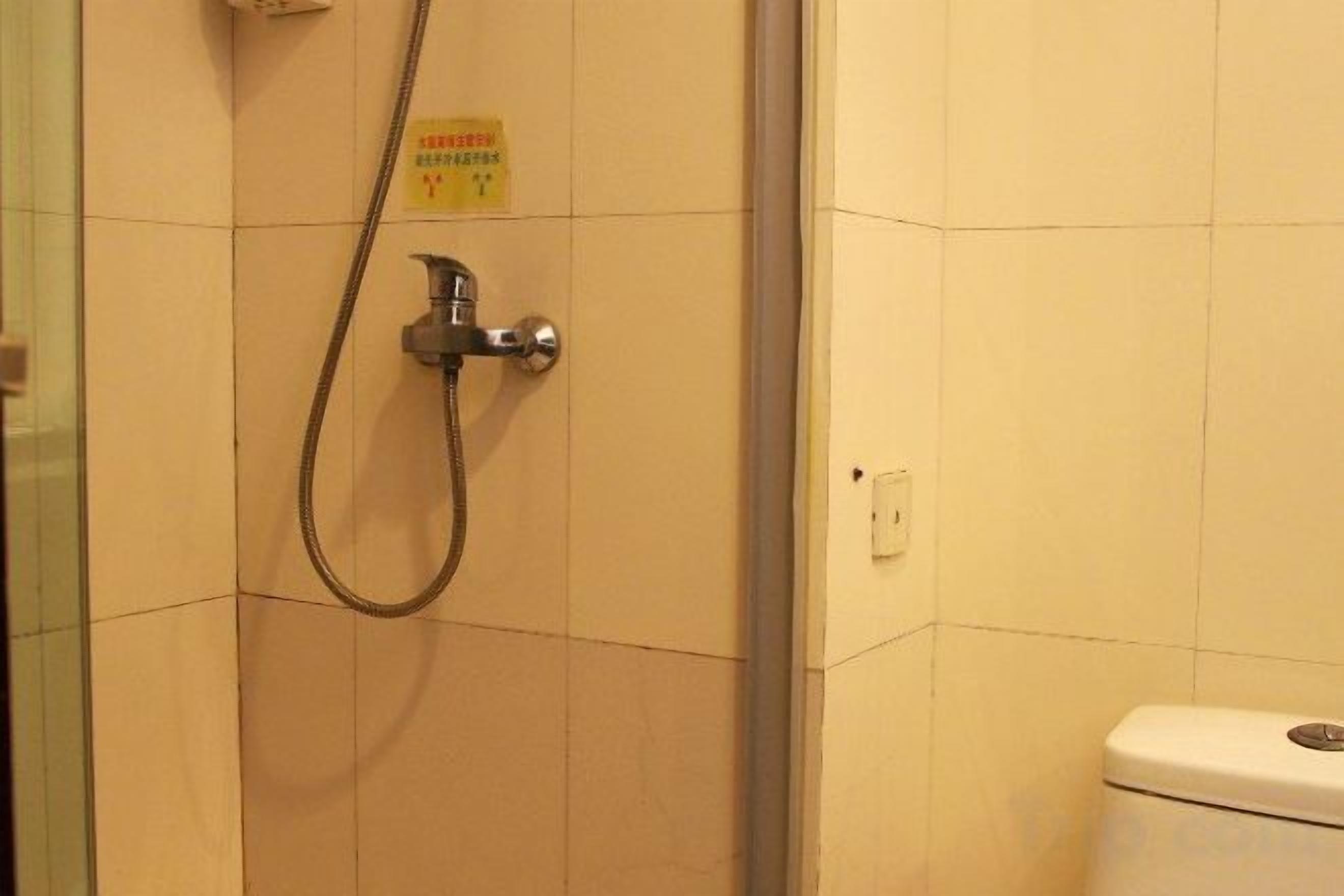 A bathroom with a shower, toilet, and a sign on the wall.