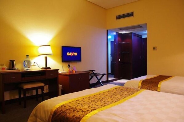 A hotel room with two beds, a desk with a lamp, a television, and a wardrobe. - Xintiandi Hotel (Haiyan)