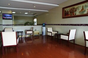 A reception area with a flat-screen TV, seating, a plant, and a painting on the wall. - Xintiandi Hotel (Haiyan)