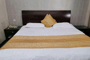 Un letto rifatto con una testiera, due cuscini e una coperta decorativa.
