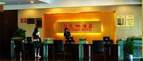 A hotel reception area with a reception desk, chairs, and a large sign with the hotel name.