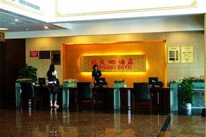 A hotel reception area with a reception desk, chairs, and a large sign with the hotel name. - Xintiandi Hotel (Haiyan)